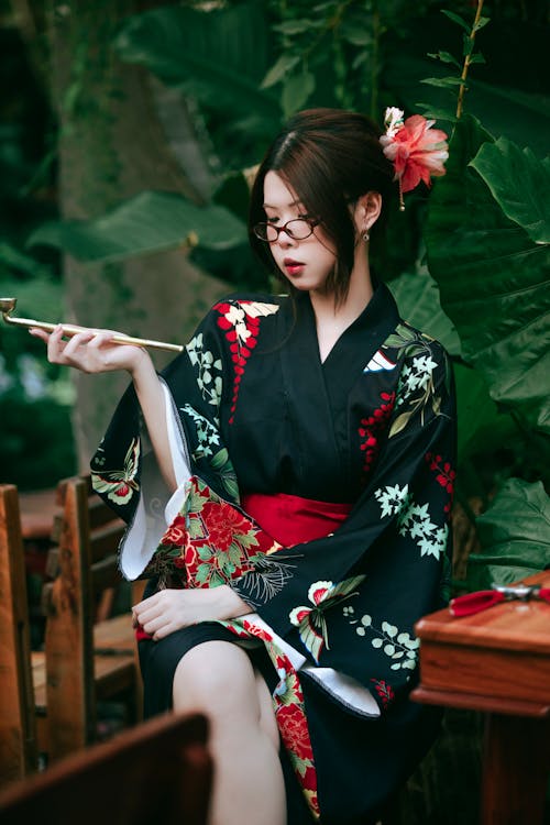 A woman in a kimono sitting at a table with chopsticks
