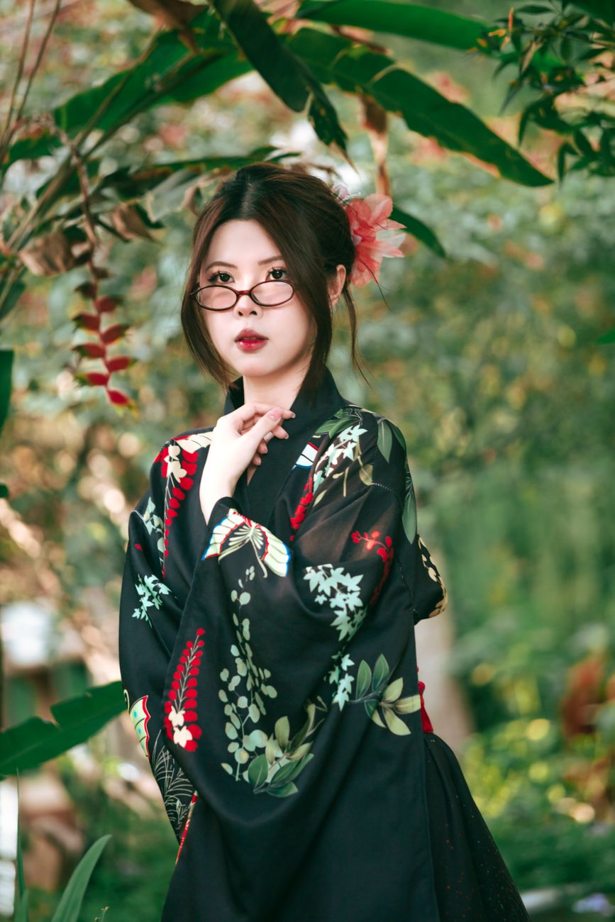 Portrait of a woman in a floral kimono posing gracefully outdoors.