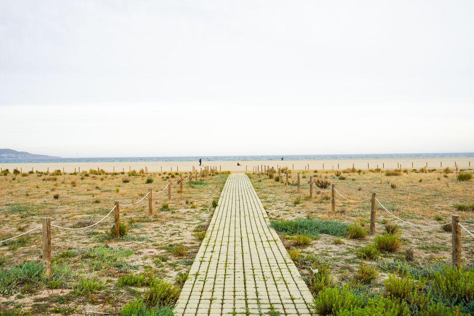Scenic beach pathway leading to the tranquil sea in Ampuriabrava, Spain.
