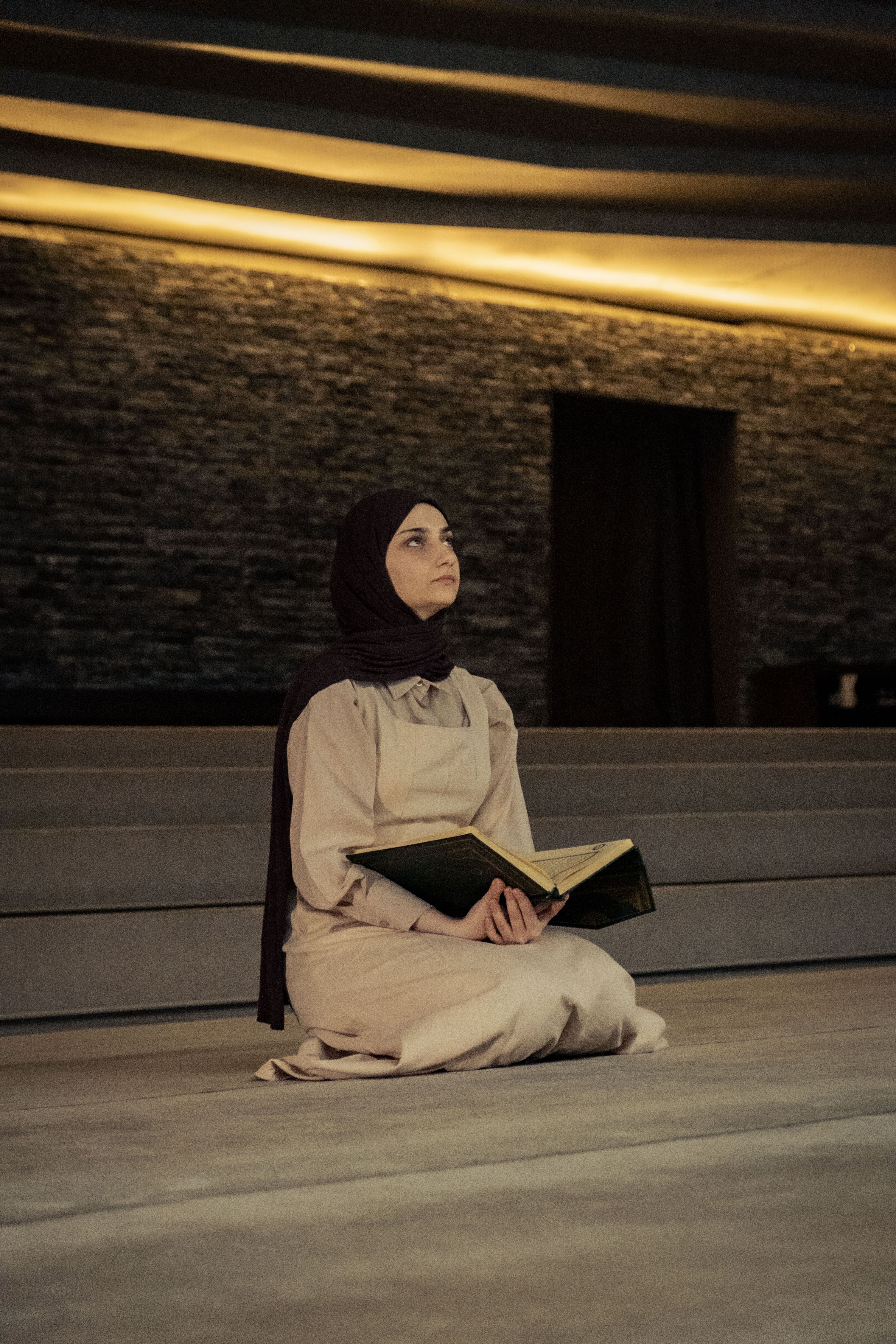 A woman in a hijab sitting on the floor with a book · Free Stock Photo