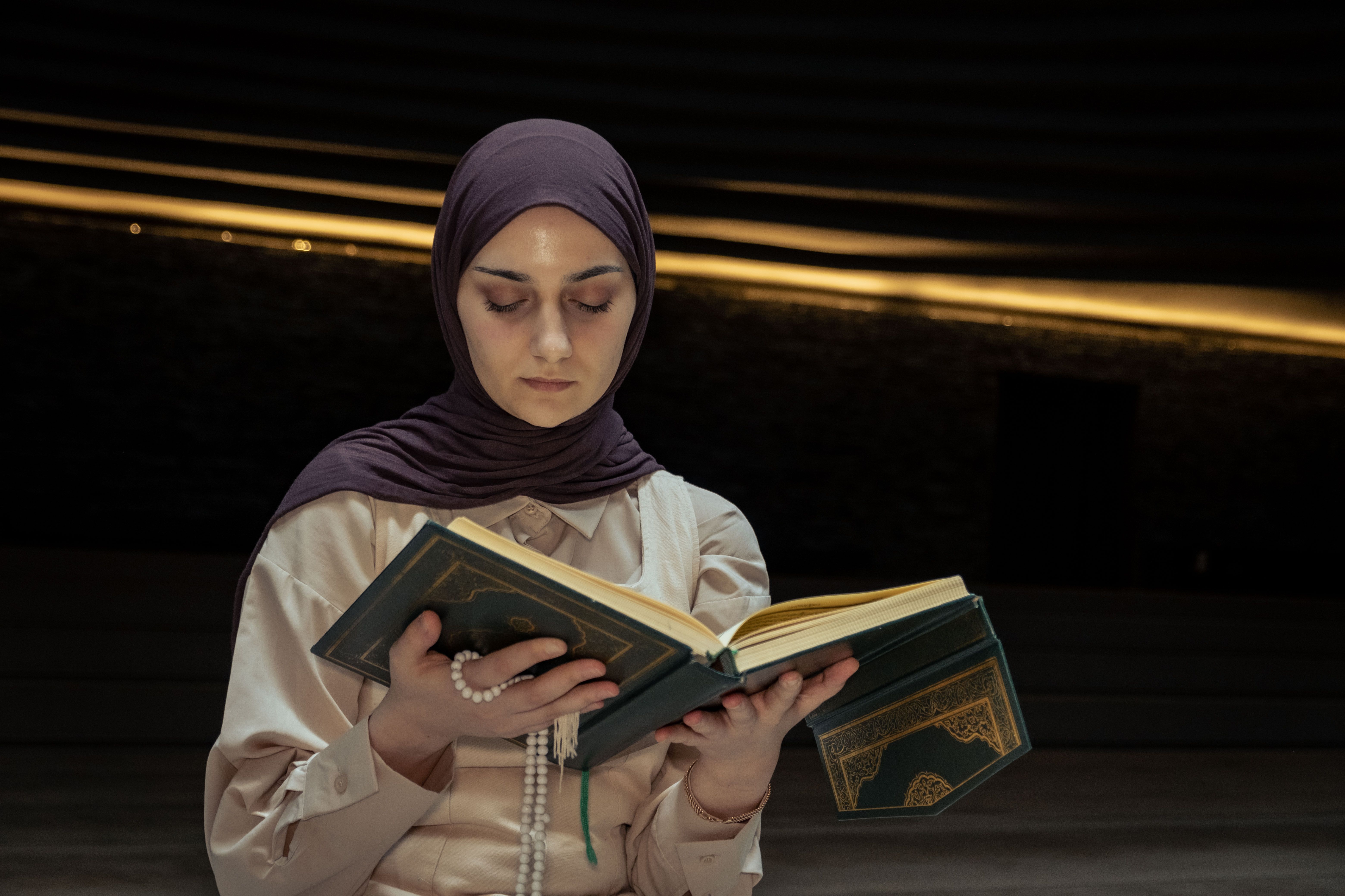 A woman in a hijab reading a book · Free Stock Photo