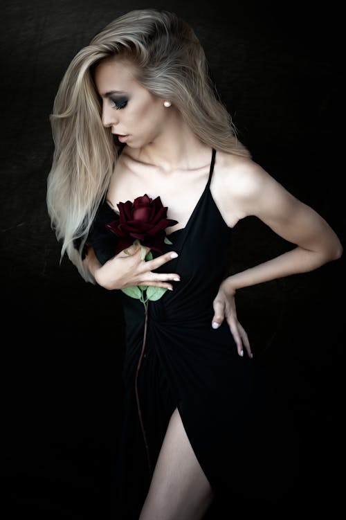 A woman in black dress holding a rose