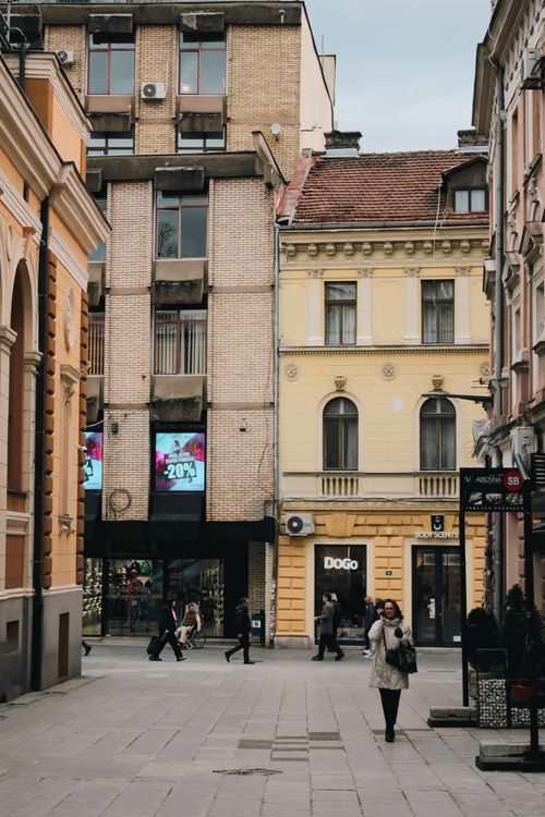 Free Bustling street in Sarajevo's city center with pedestrians surrounded by historic buildings and shops. Stock Photo