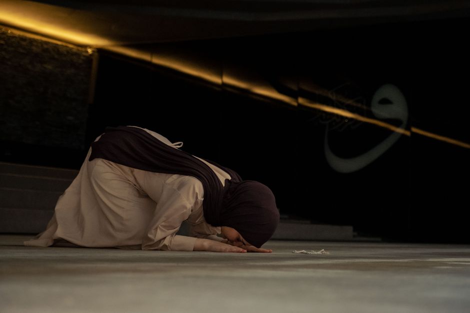 Woman respectfully covering her hair with a scarf outside a mosque in Kuwait