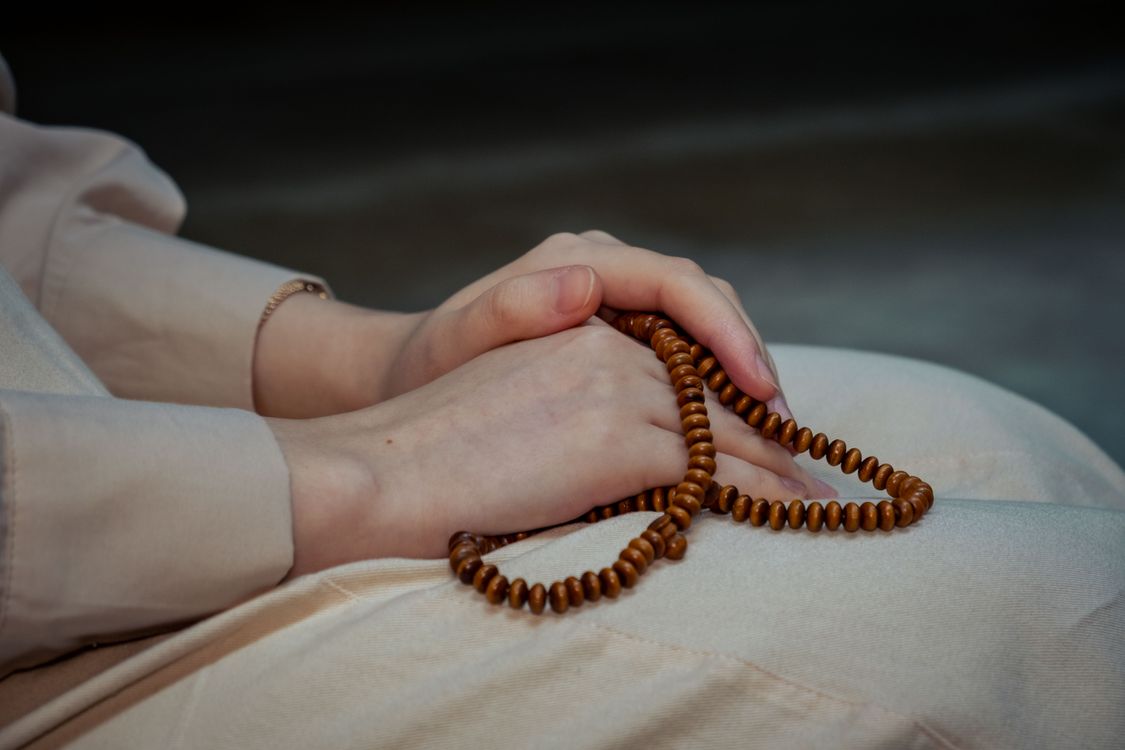Person in Modest Gown Sitting and Holding Prayer Beads · Free Stock Photo