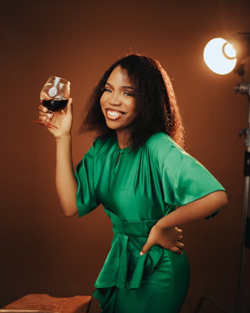 A woman in a green dress holding a glass of wine