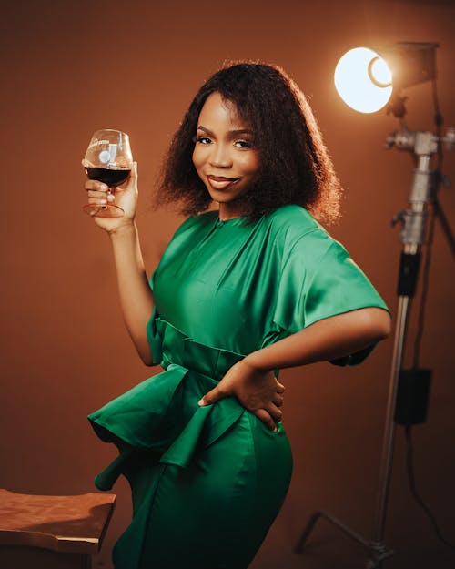 A woman in a green dress holding a glass of wine
