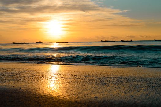 Beautiful sunset over Cumuruxatiba beach with boats on the ocean in Brazil.