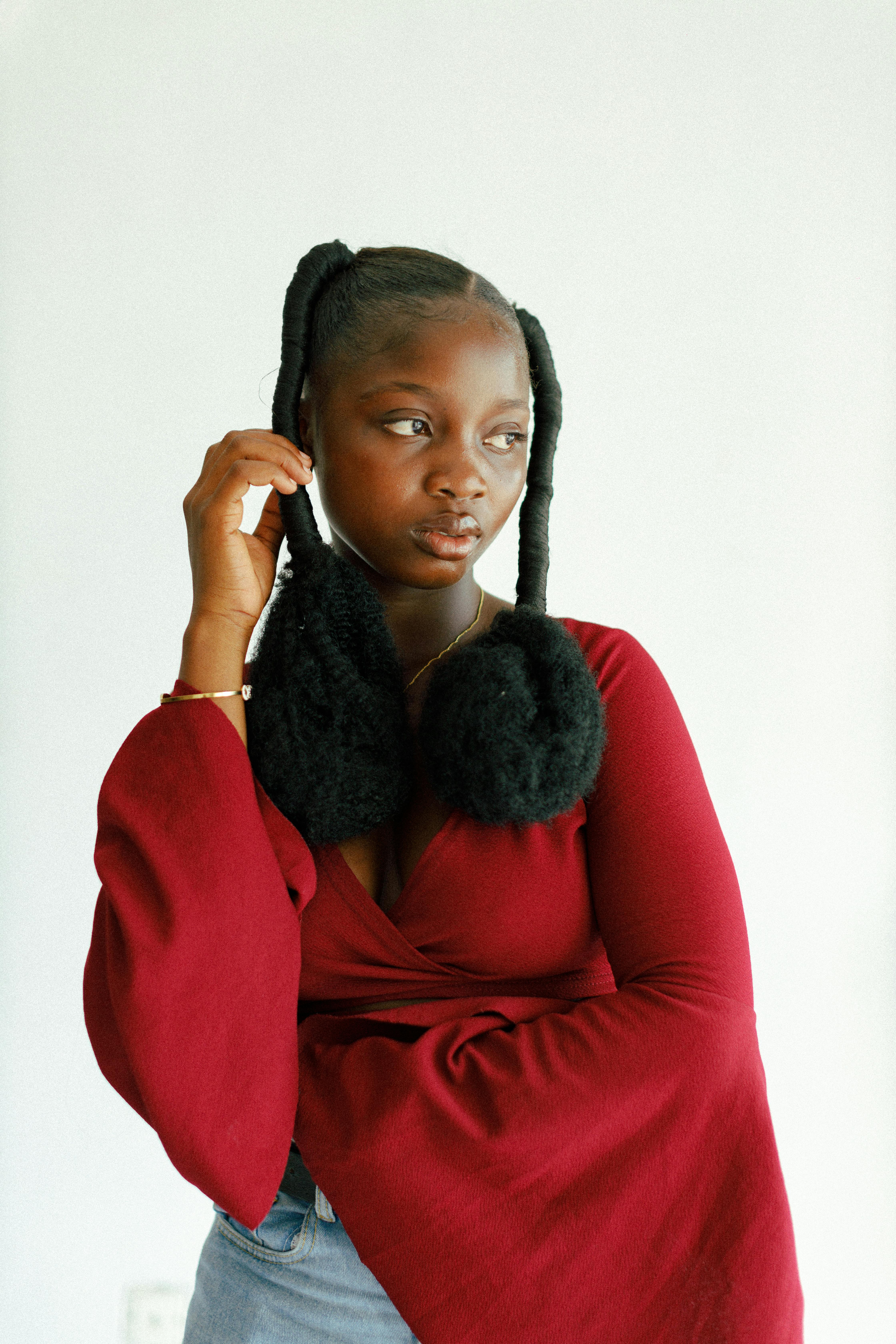 Fashionable African woman posing confidently in a red outfit against a clean background.