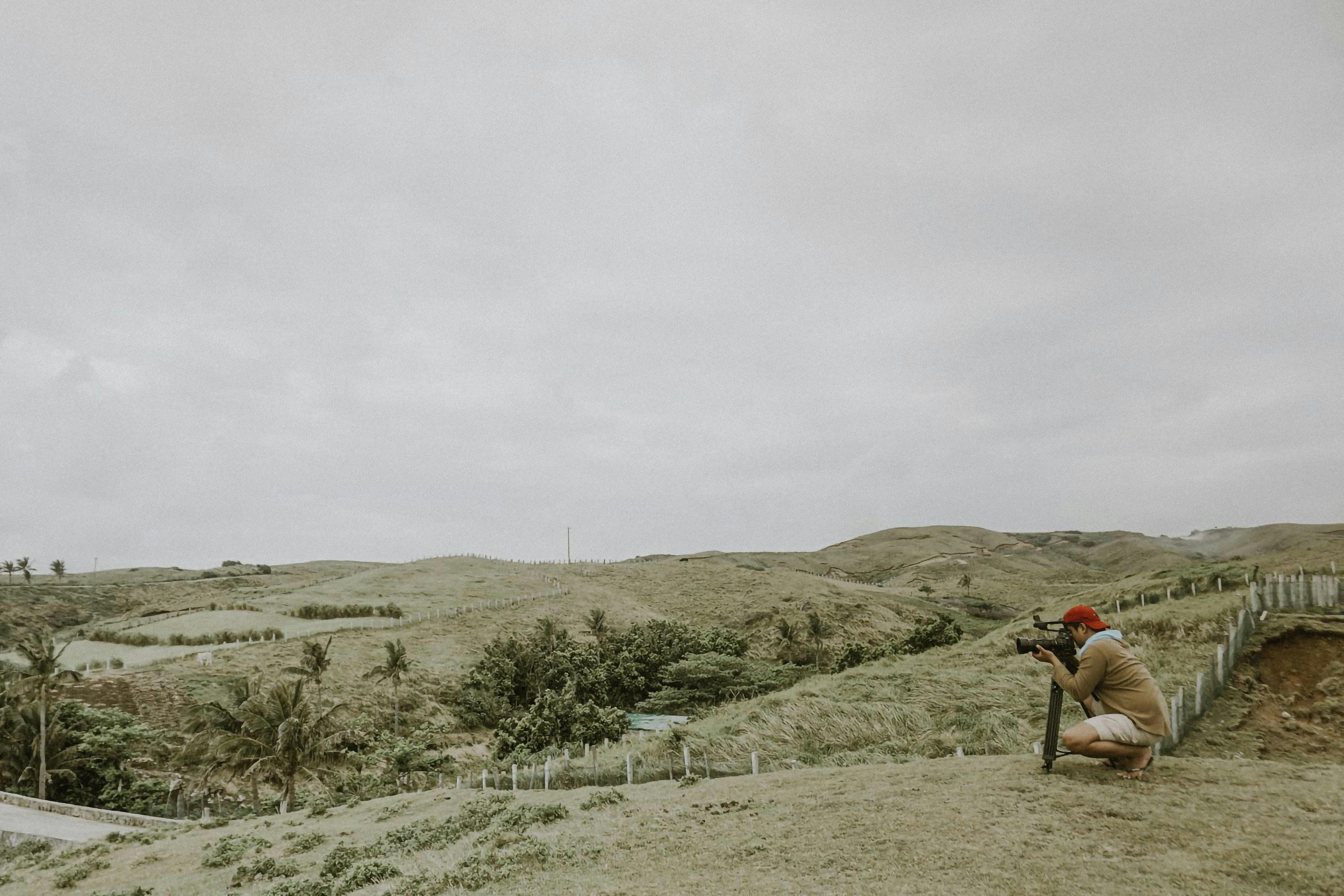 man squatting and photographing countryside