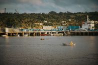 A serene view of Basco harbor in the Philippines with a rowboat and lush greenery.