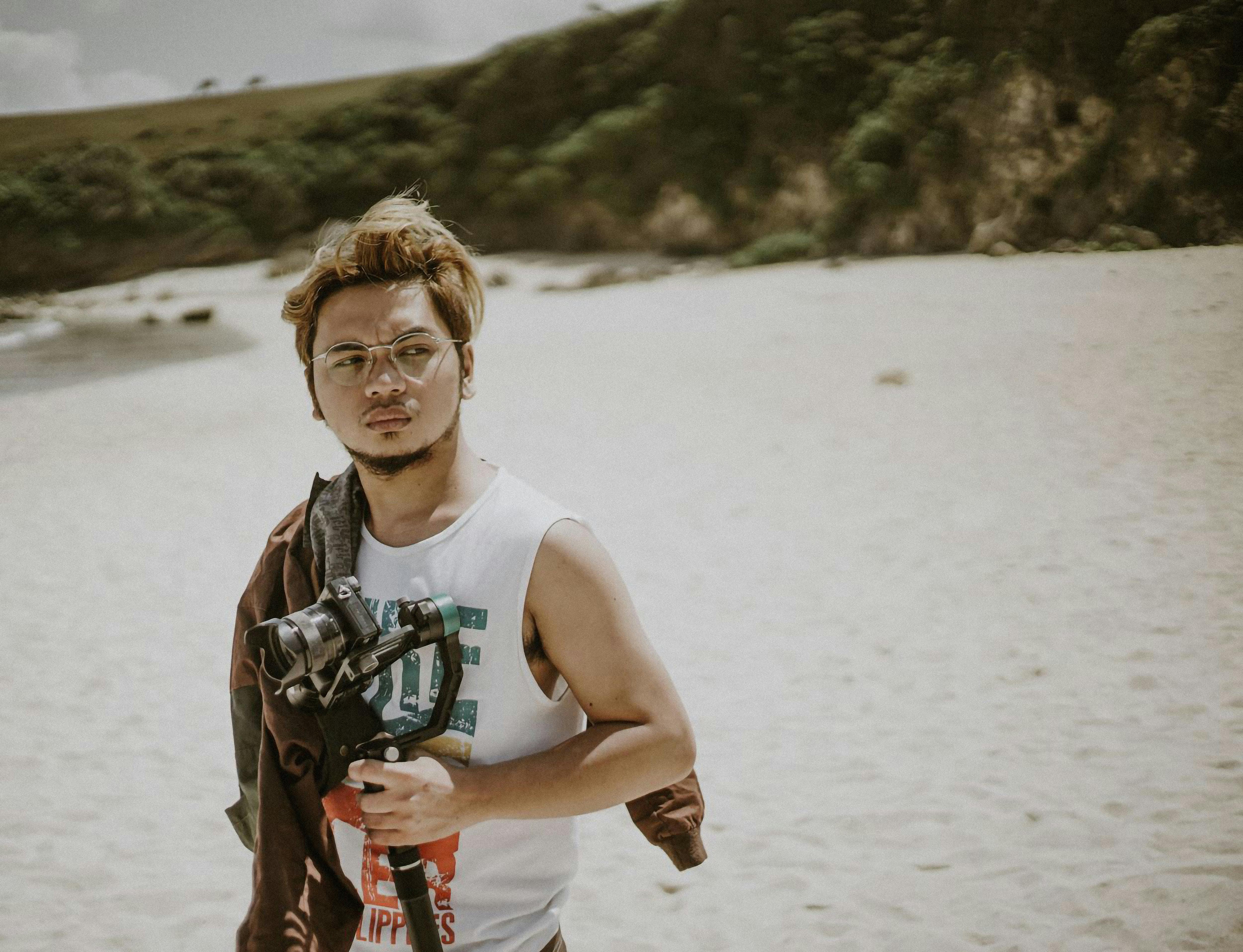 Young man with camera on Basco beach, capturing the essence of photography amidst nature.