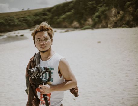 Young man with camera on Basco beach, capturing the essence of photography amidst nature.