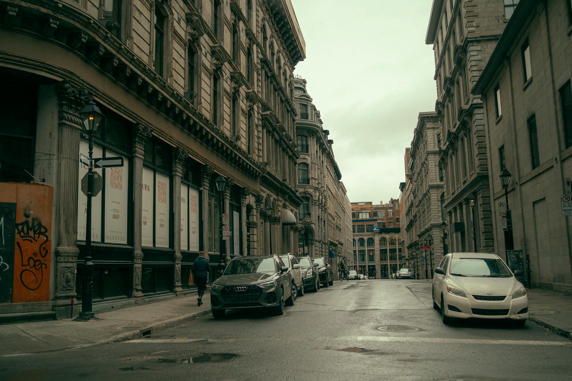 Classic cityscape in Montreal showcasing historic urban architecture and parked cars on a rainy day.