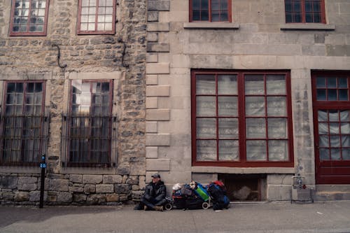 A couple of people sitting on the sidewalk outside of a building