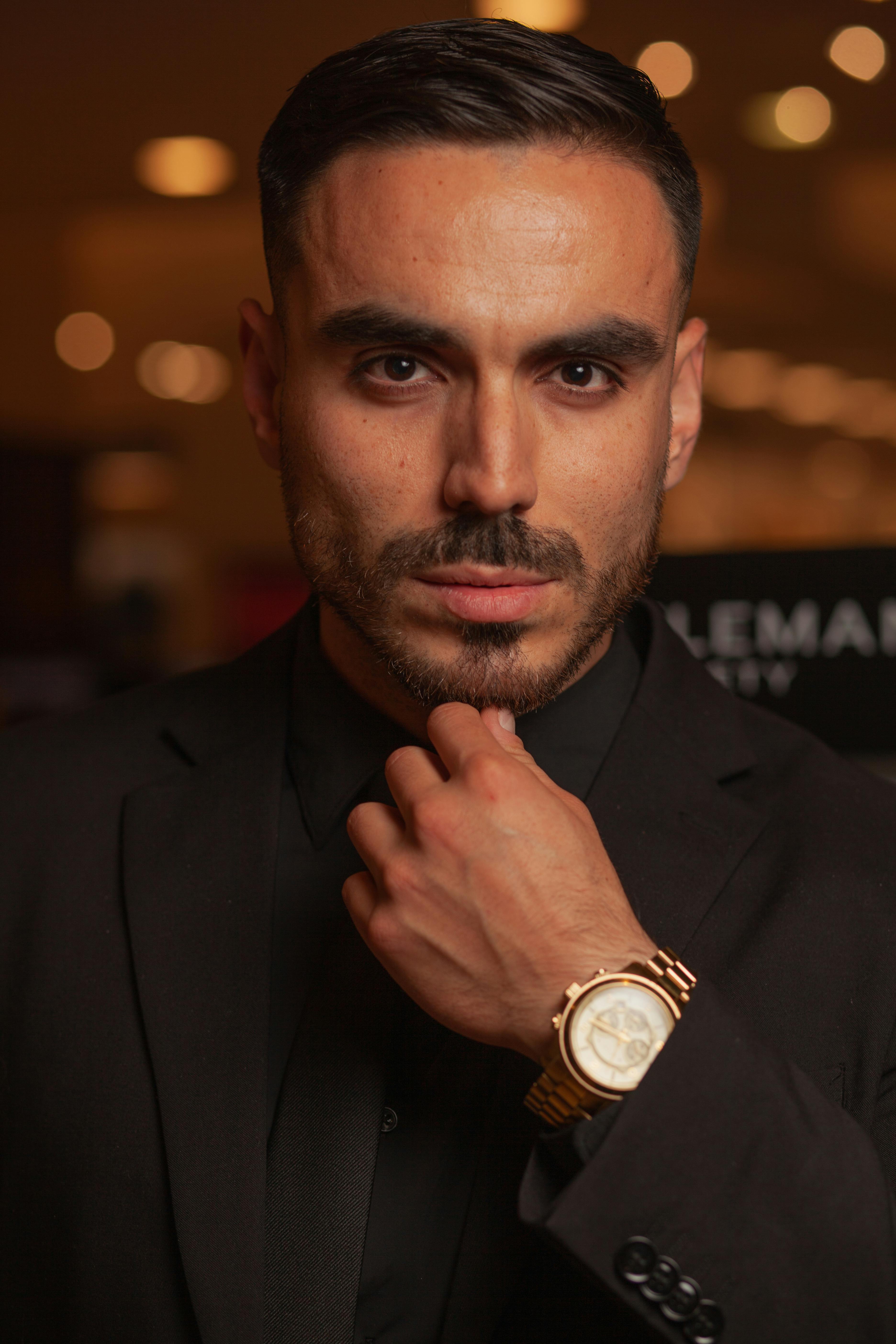 Portrait of a stylish man in black suit with gold wristwatch. Captivating and professional look.