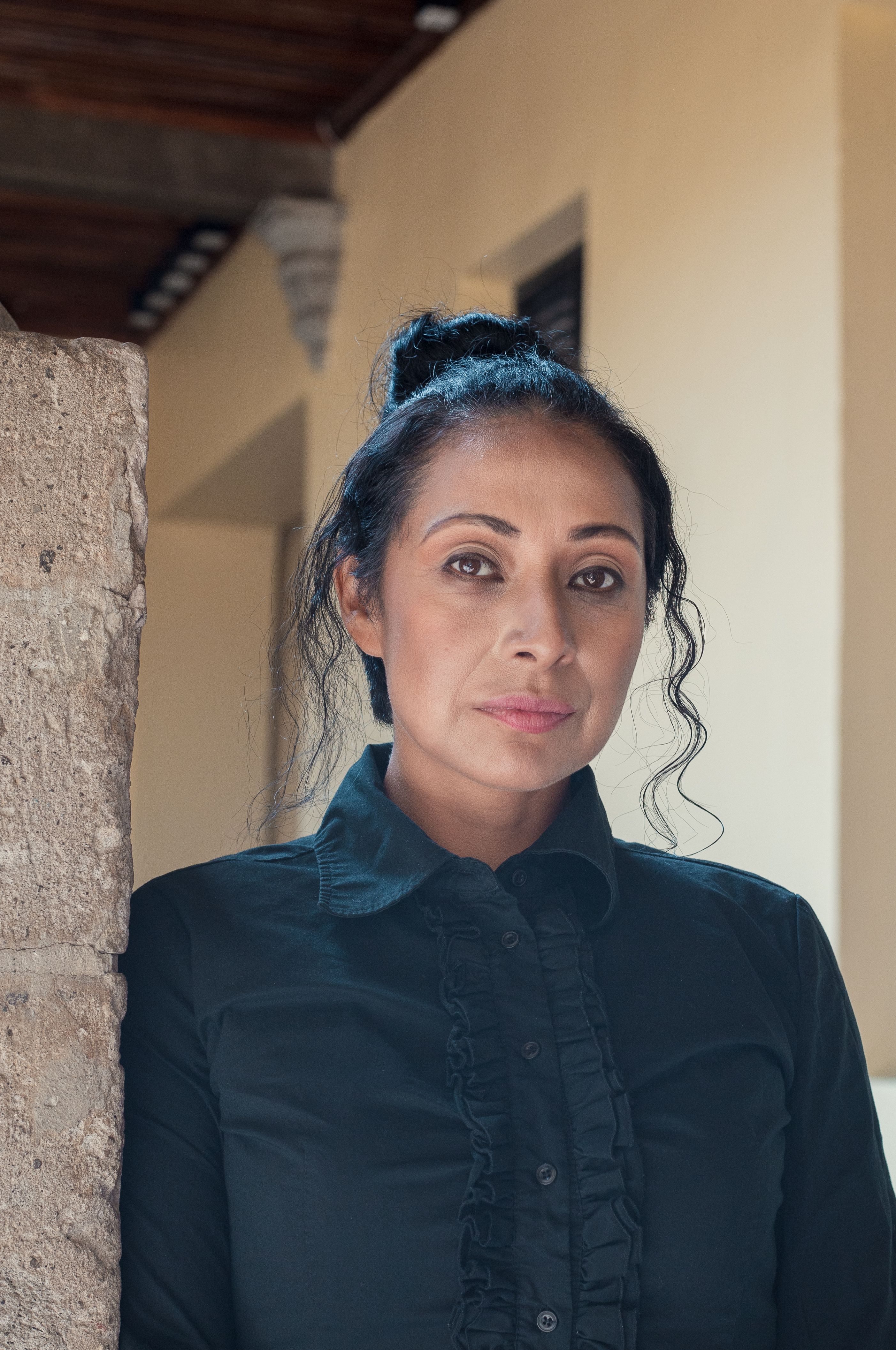 Elegant portrait of a woman in México City, showcasing style and poise in a neutral setting.
