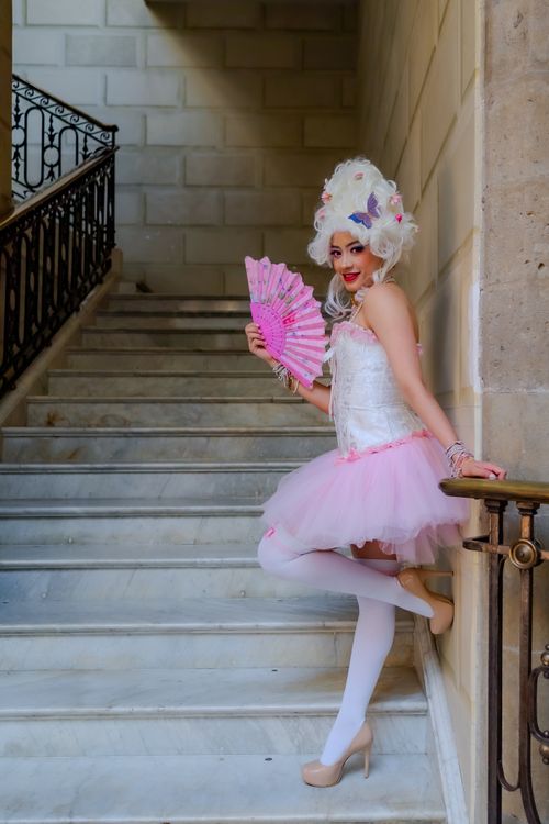 Free A woman in an elegant costume poses on a grand staircase, exuding grace and style. Stock Photo