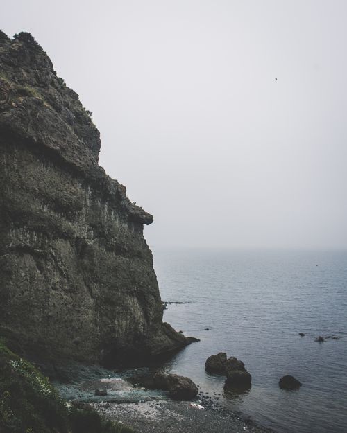 Foggy cliffs above a calm sea, photo by Emre Can Acer on Pexels