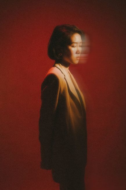 Artistic portrait featuring a woman in blurred motion against a red background, conveying a dream-like effect.