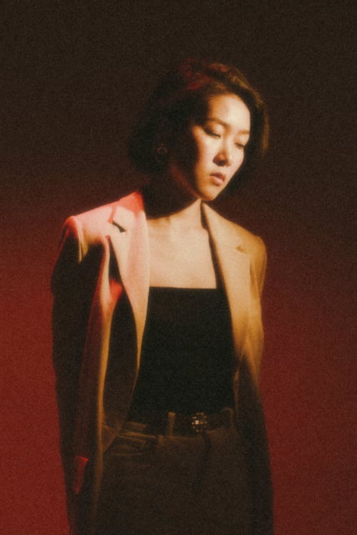 A woman in a jacket and blazer standing in front of a red light