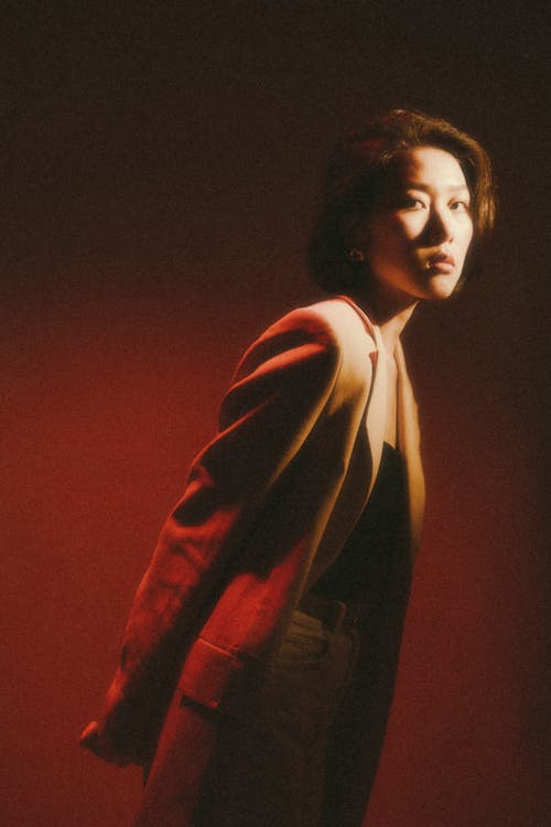 A woman in a jacket and pants standing in front of a red light