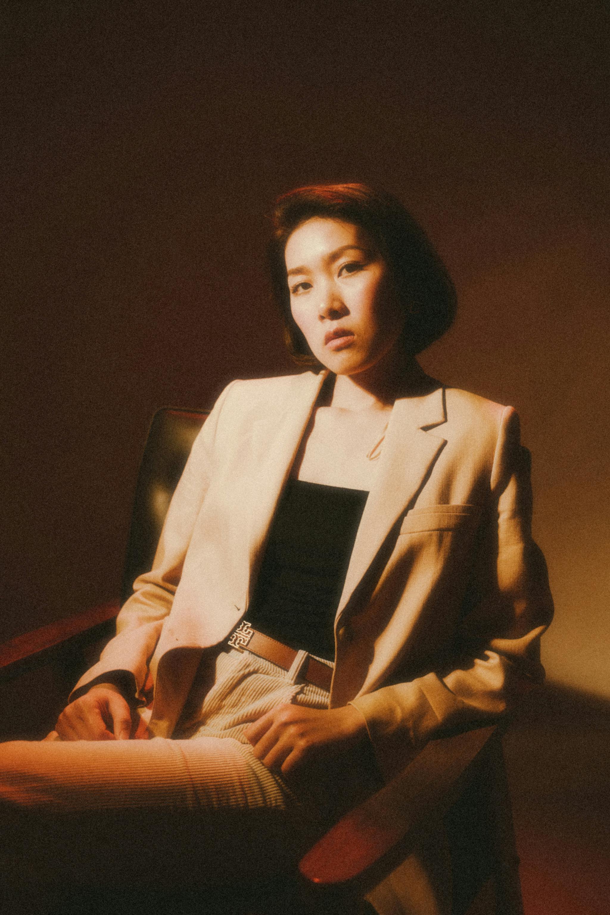 Elegant woman in a beige suit posing confidently in a retro setting.