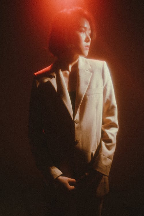 A woman in a suit with red light shining on her