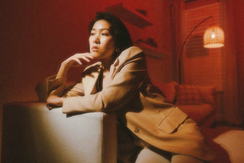A woman sitting on a couch in a room with red lighting