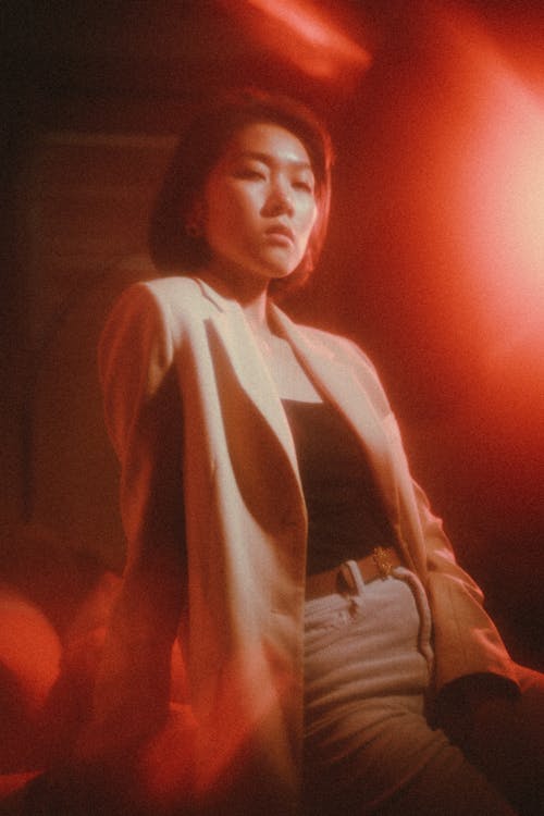 A woman in a jacket and jeans sitting in front of a red light