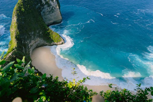 A beach with a cliff and a blue ocean