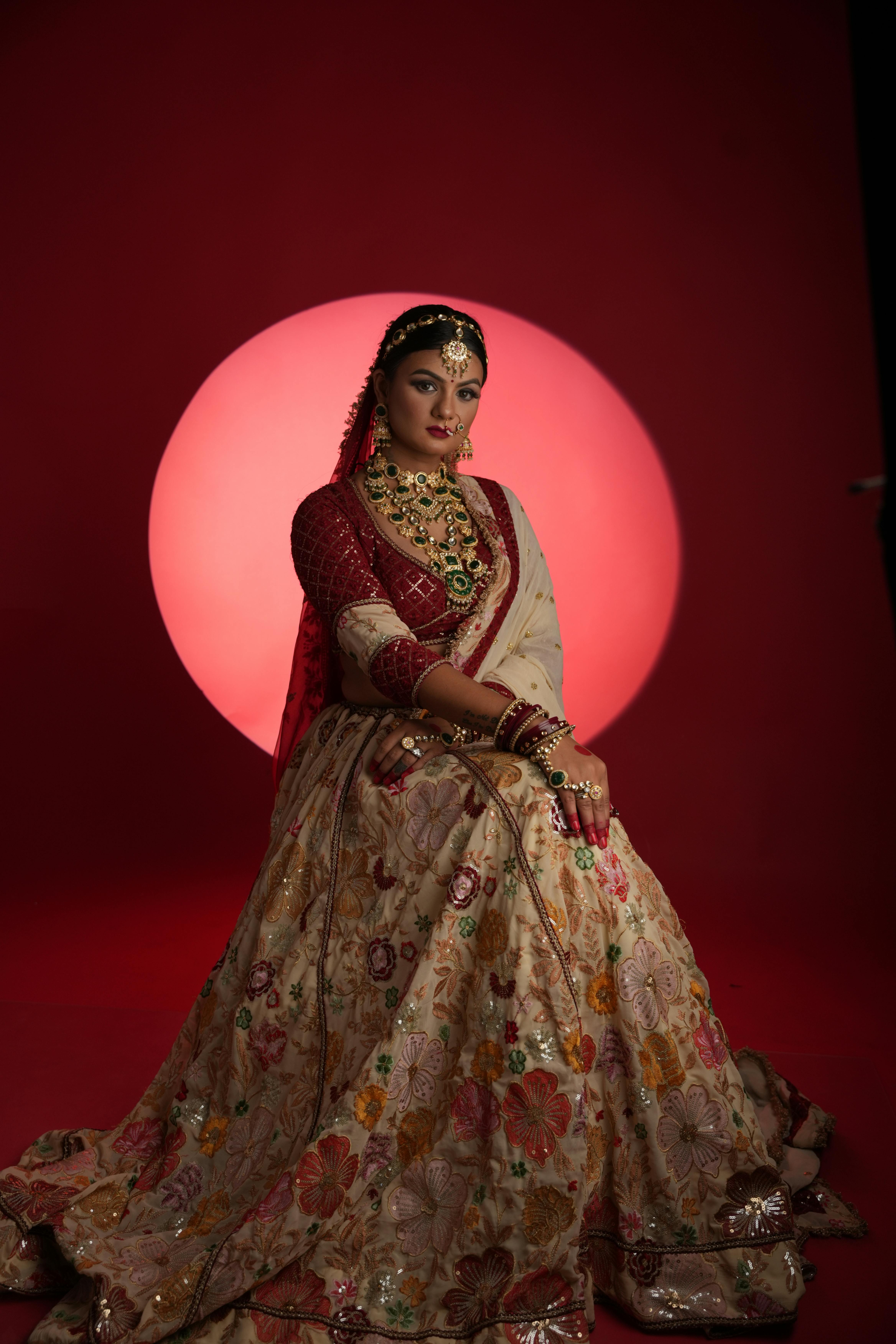 Red embroidered crop-top blouse styled with floral lehenga for bridal portrait