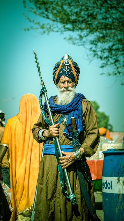 An old man in turban and beard holding a gun