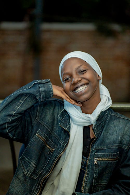 A smiling woman in a denim jacket and headscarf