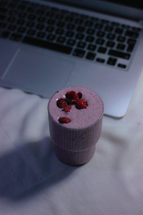 A cup of smoothie with raspberry and pomegranate seeds