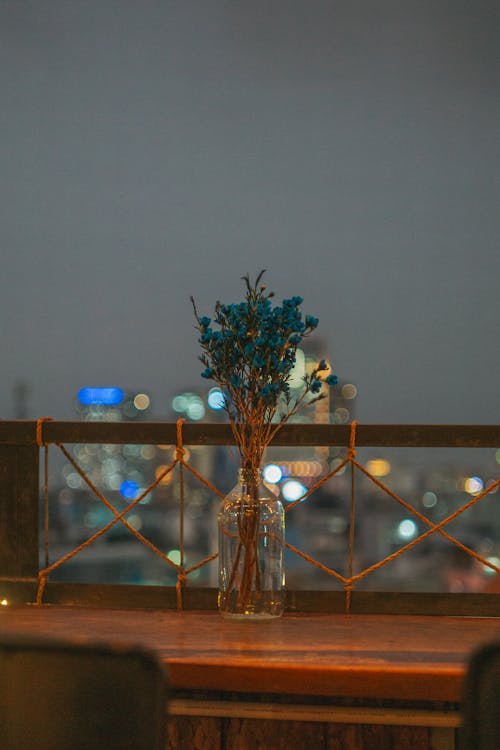 A vase with flowers on a table with a view of the city