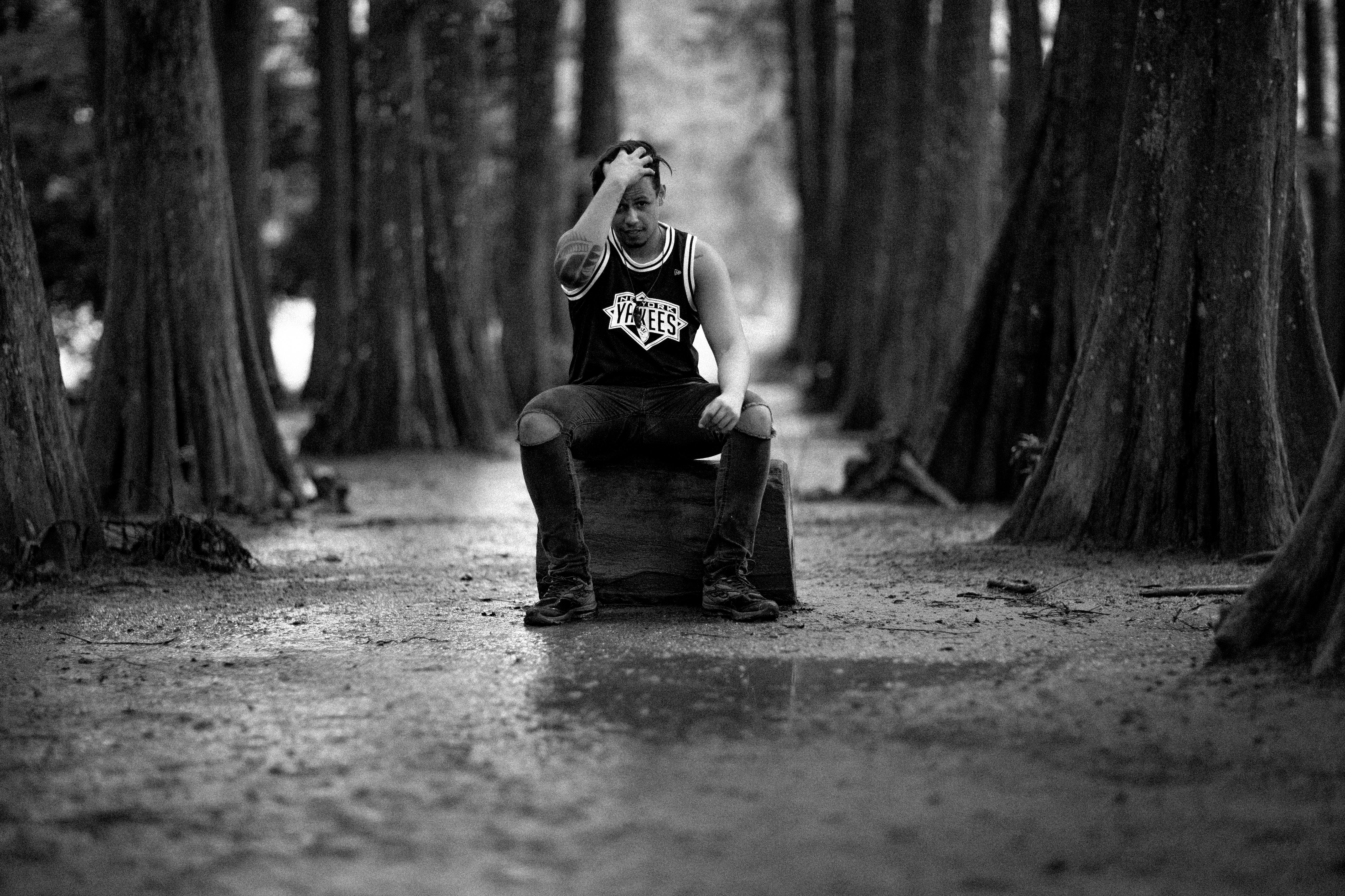 一名男子坐在森林里，拍摄时尚的黑白肖像照片