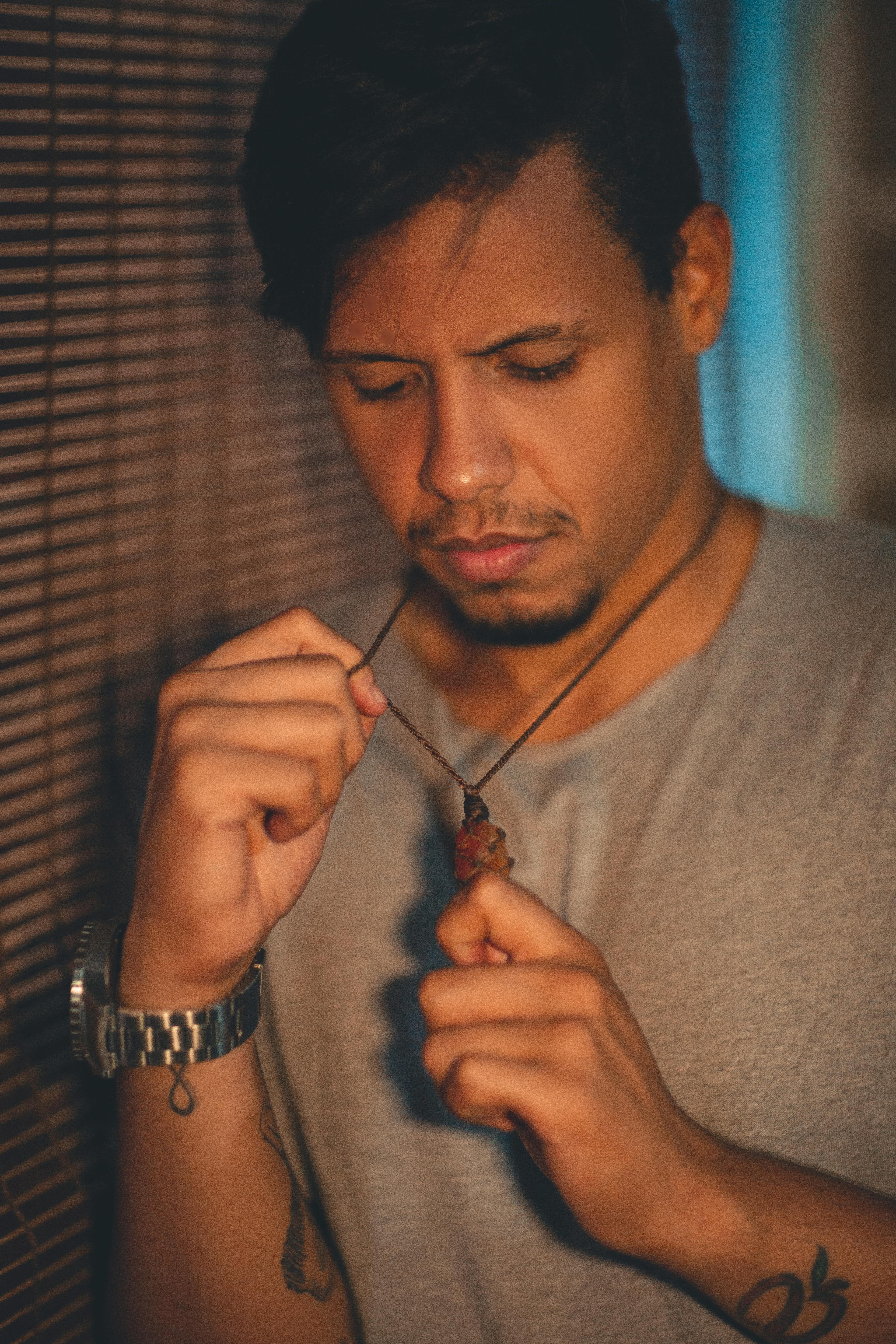 一个年轻人在休闲环境中拿着项链，陷入深思