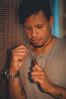 一个年轻人在休闲环境中拿着项链，陷入深思