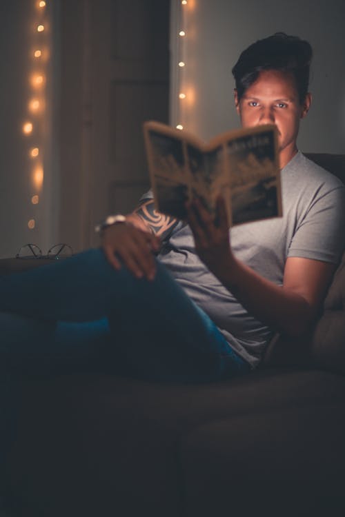 Person, Die Auf Sofa Sitzt Und Papier Hält