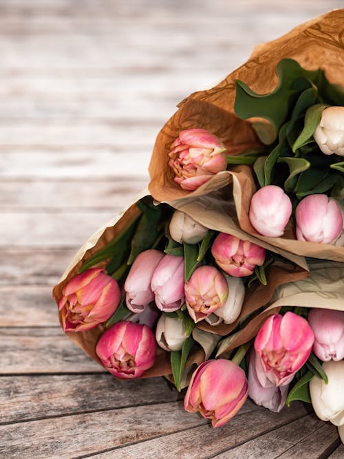 A bouquet of pink and white tulips on a wooden table