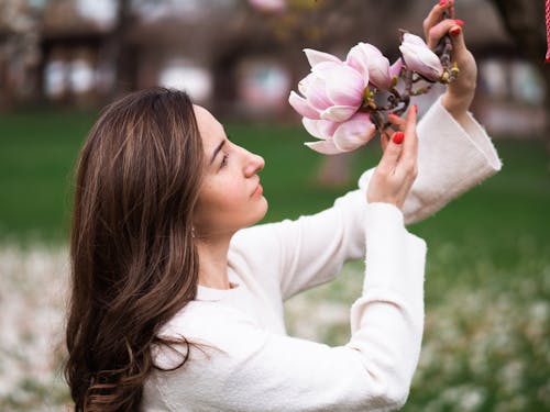 A woman is holding a magnolia flower