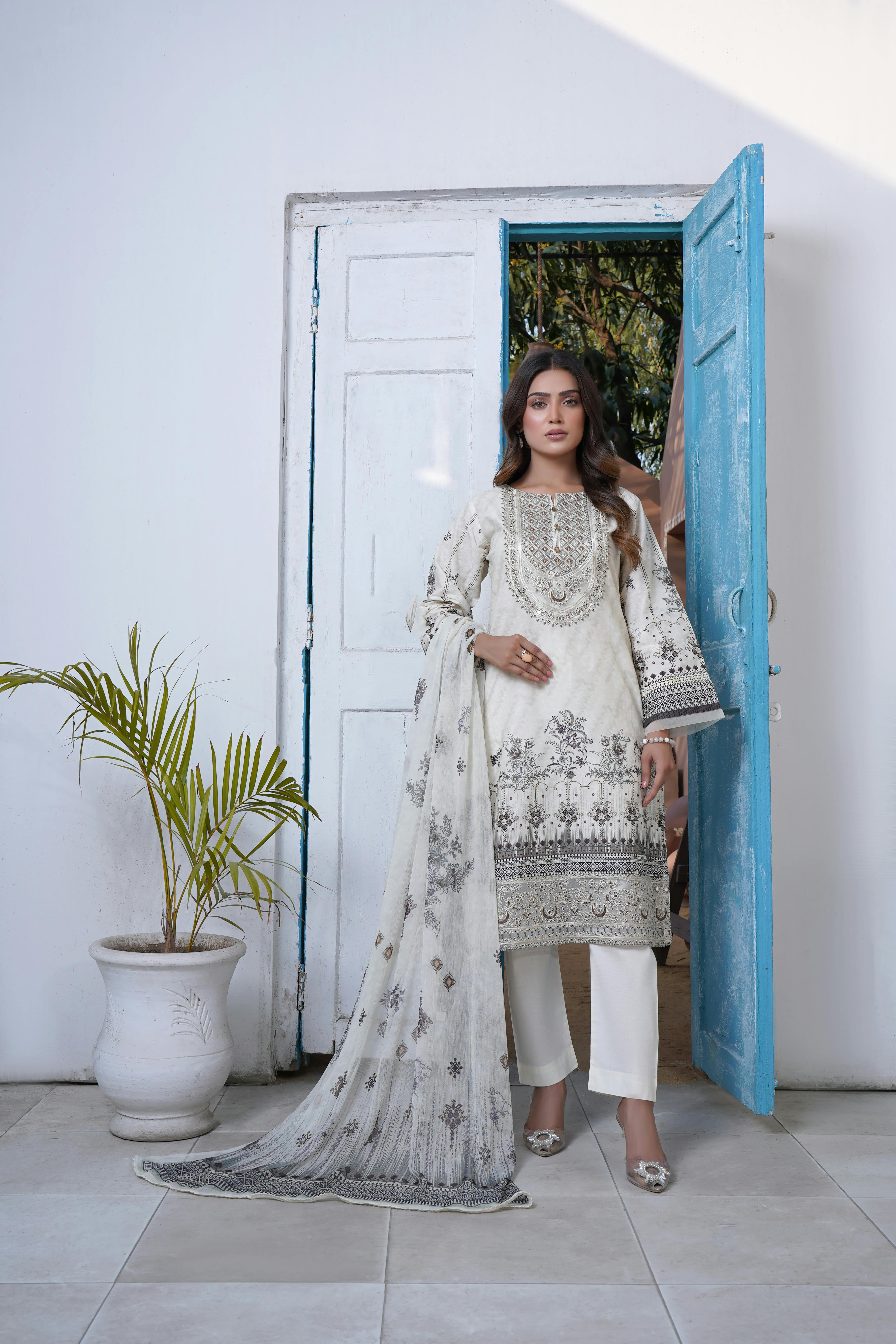 woman standing in white traditional clothing and shawl in front of doorway