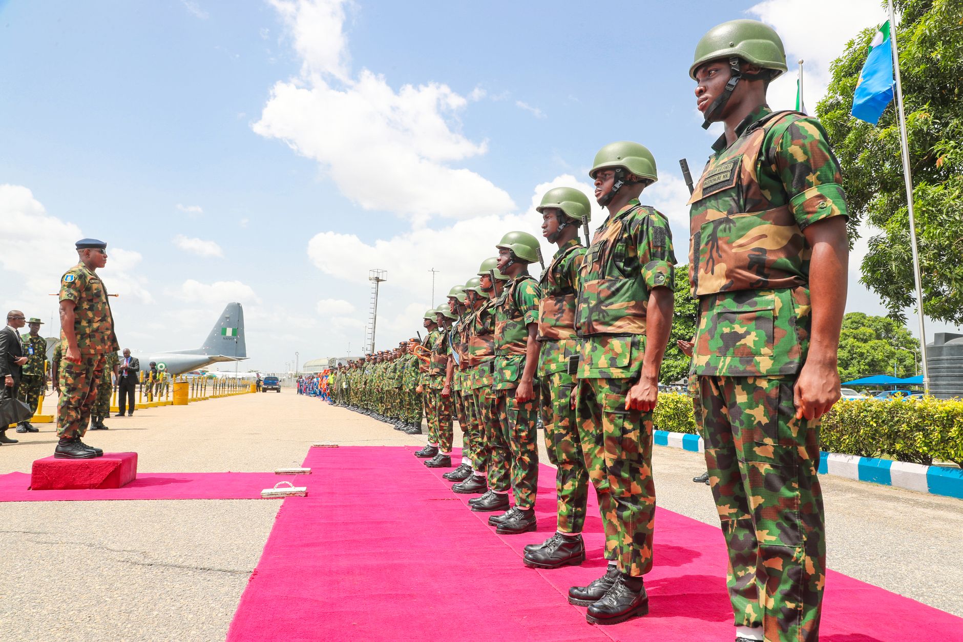 Nigerian soldiers standing at attention during a military ceremony outdoors.