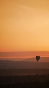 Captivating view of a hot air balloon silhouetted against a stunning African sunset.
