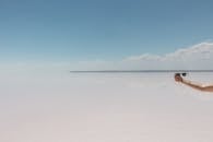 晴朗的天空下，宁静的海滩上，一只手拿着太阳镜