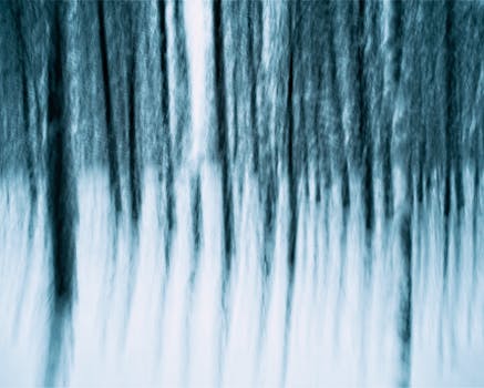 Dreamlike abstraction of a winter forest with blurred vertical tree patterns.