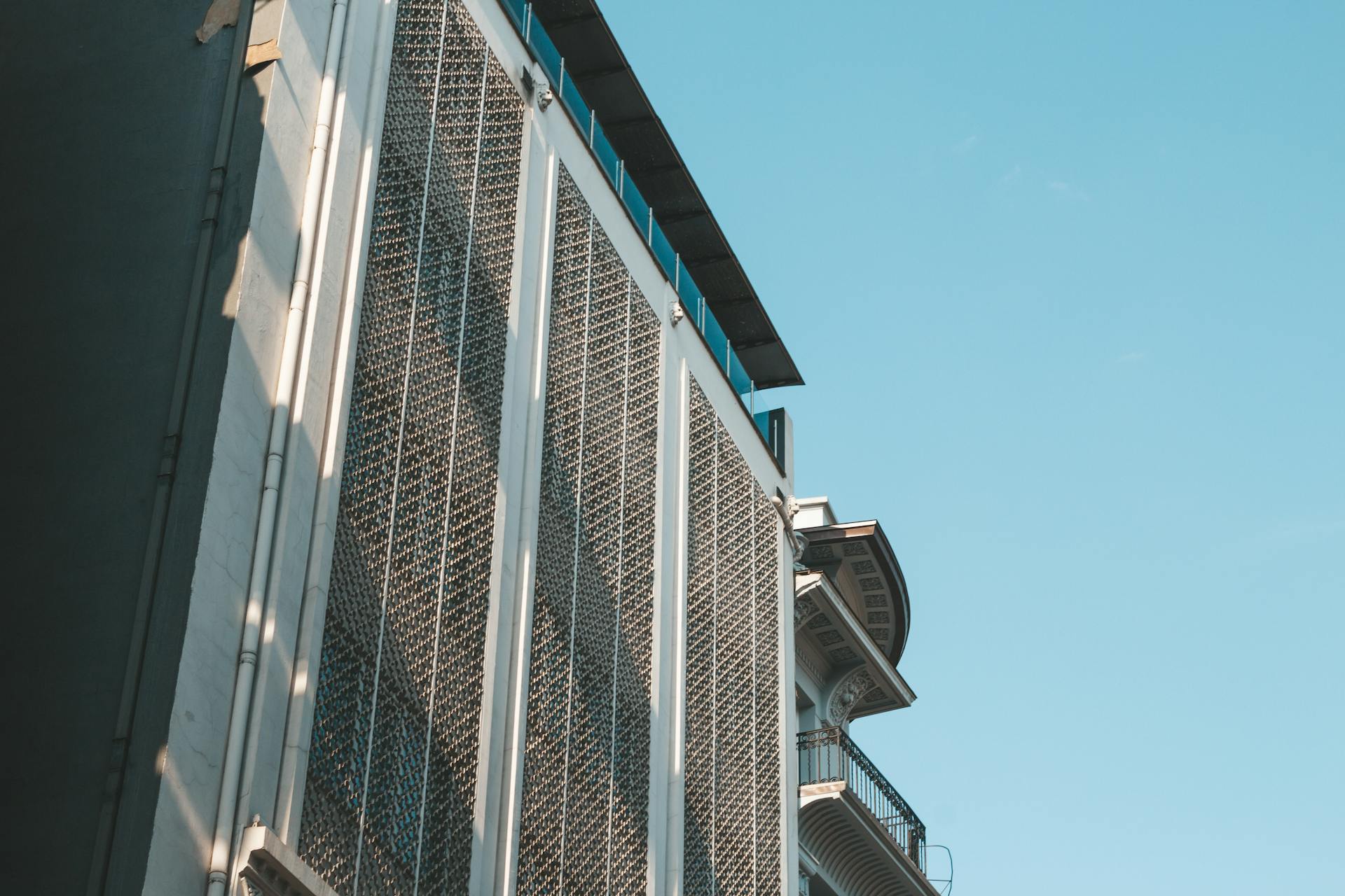 A modern architectural facade with intricate details highlighted against a clear blue sky.