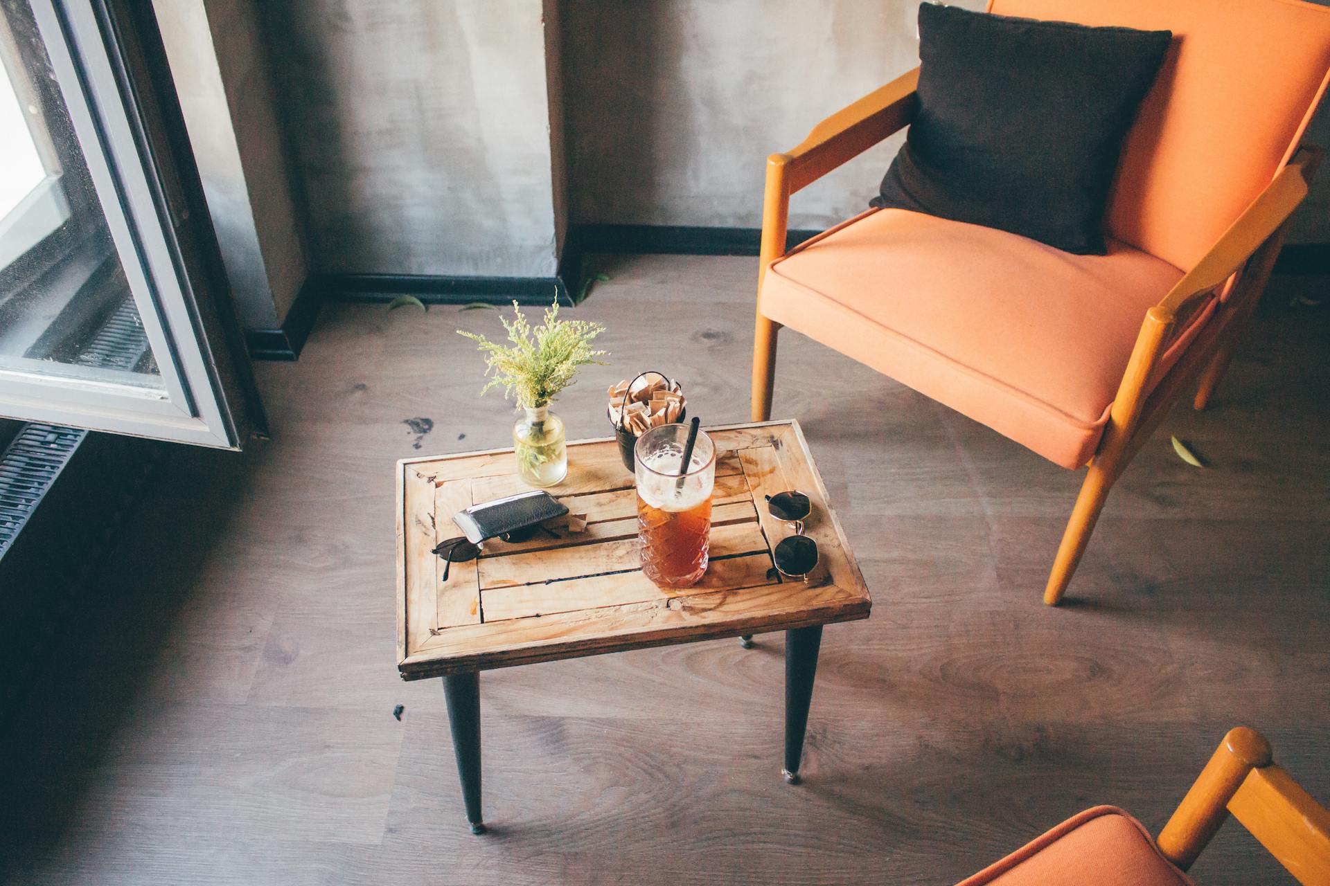 A warm, inviting lounge space featuring orange chairs, wooden table, and a refreshing drink.