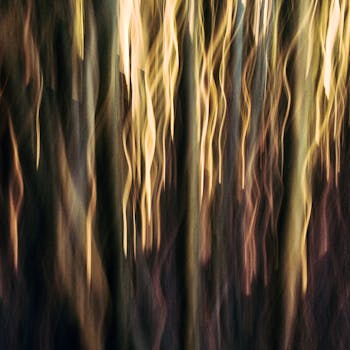 Dreamlike image of an abstract forest with mystical vertical streaks and warm tones.